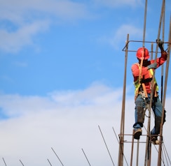 man wearing red hard hat hanged on brown rebar bar