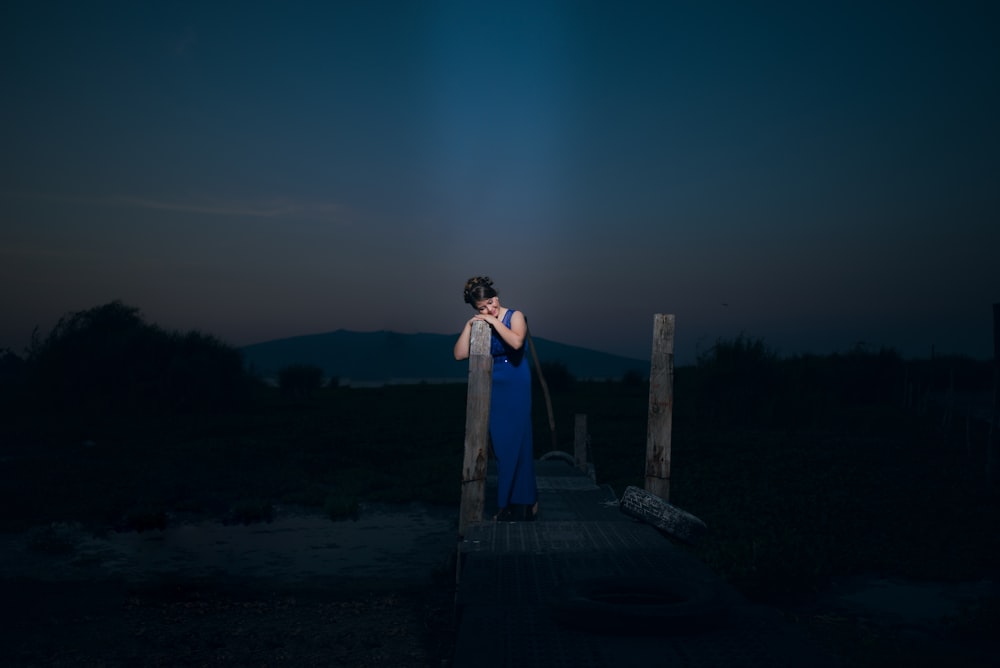 woman stands on wooden dock during night