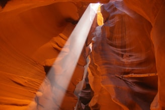 A stunning sunbeam piercing through the narrow, wavy sandstone walls of Antelope Canyon.