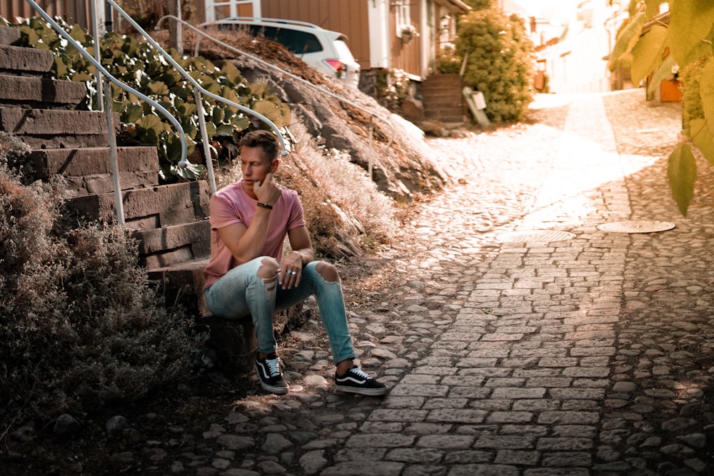 man sitting at the bottom of stair at daytime