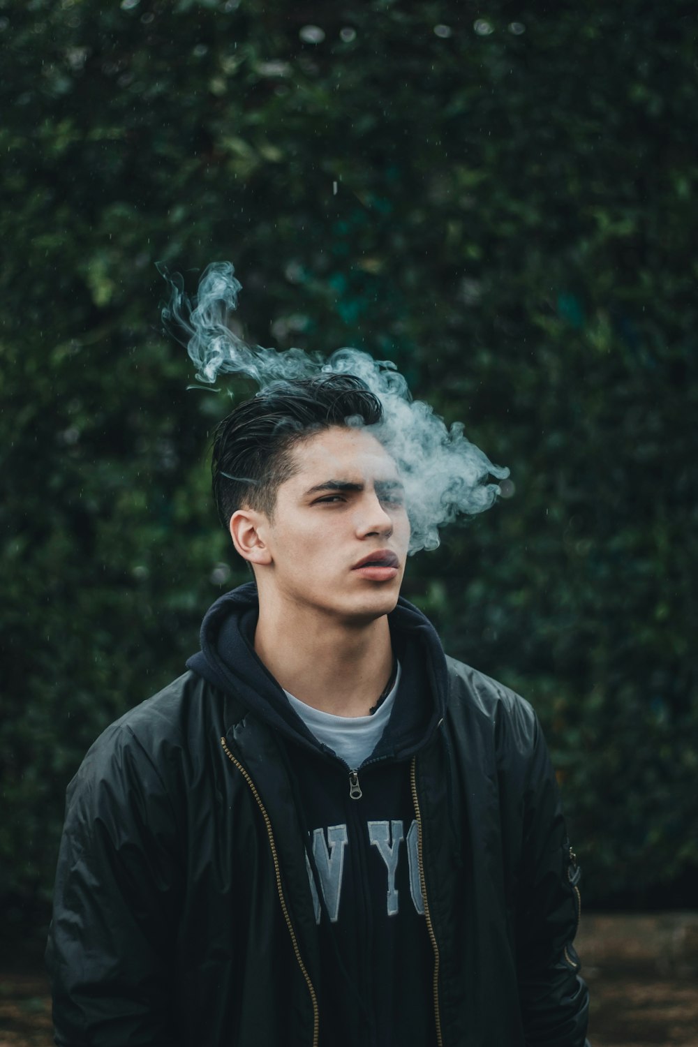 man smoking near green leaf trees