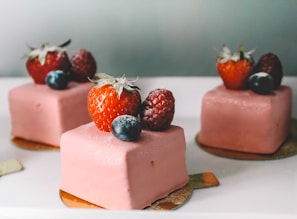 three square pastry with strawberries on top platter