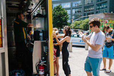 Happy customers enjoying meals at an outdoor food stand on a sunny day.