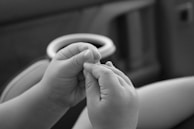 Close-up of hands performing gentle respiratory physiotherapy on an infant.