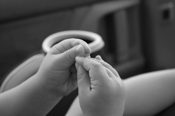 A close-up of gentle hands holding a set of colorful, safe baby teething accessories
