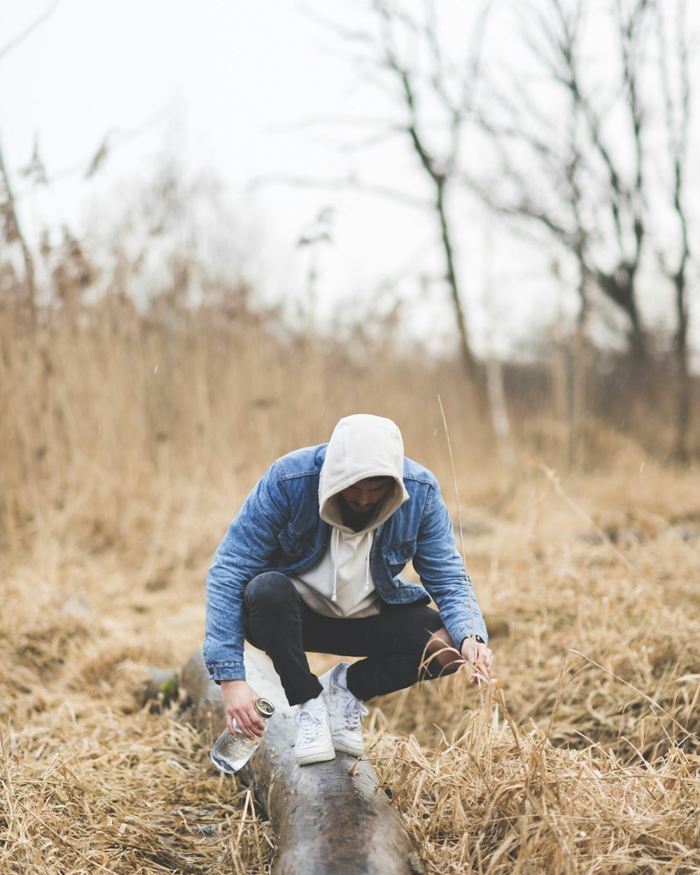 man wearing blue denim jacket holding bottle