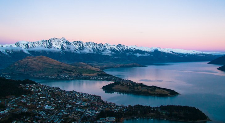 Queenstown town and Lake Wakatipu at dusk with the snow-capped Remarkables range behind, July