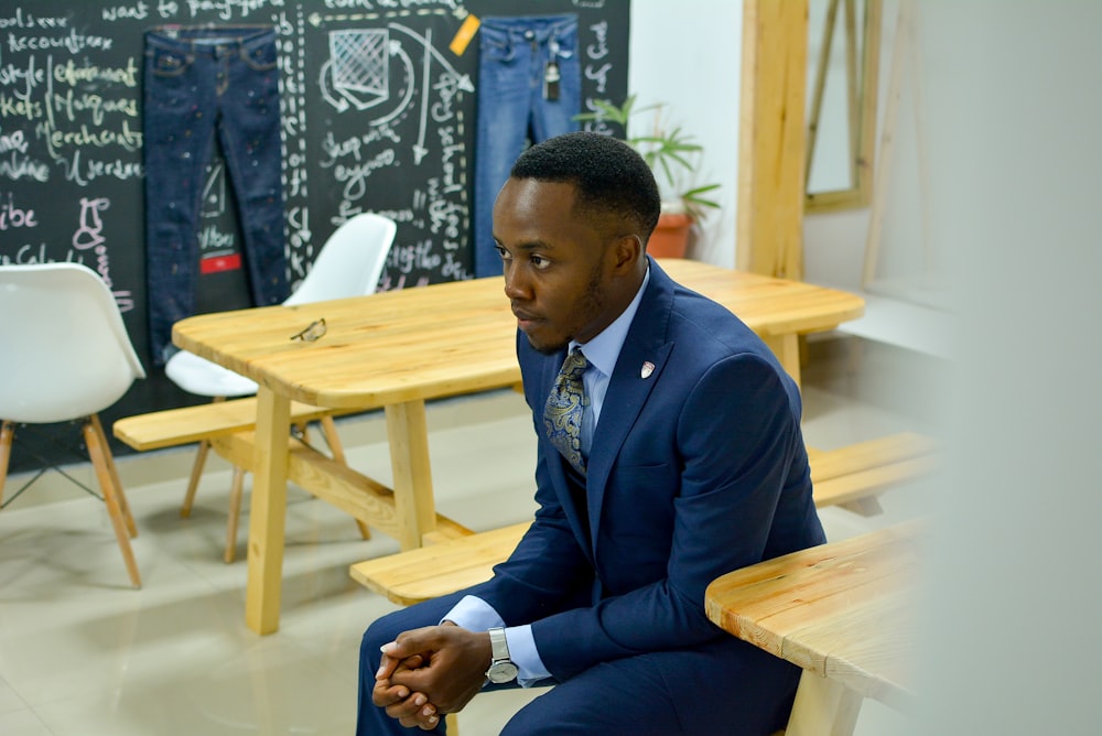 man in blue suit jacket sitting on bench