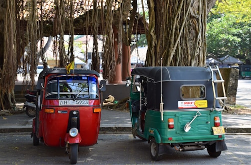 two assorted-color auto rickshaws parked on sidewalk