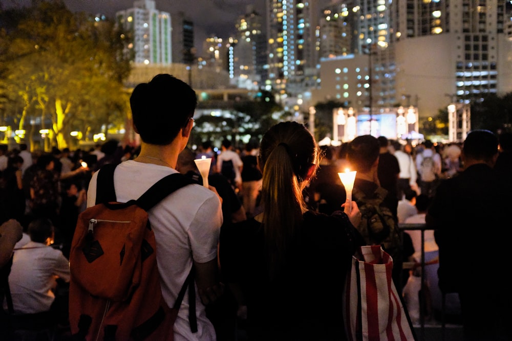 group of people holding candle near buildings