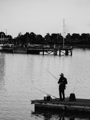 A scenic view of a dock with fishing gear and a phone resting on the railing.
