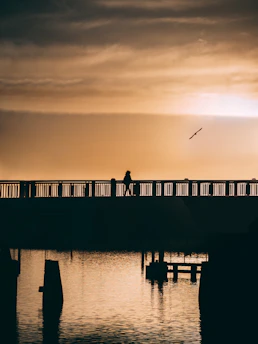 A person walking confidently across a bridge at sunrise, representing new beginnings.