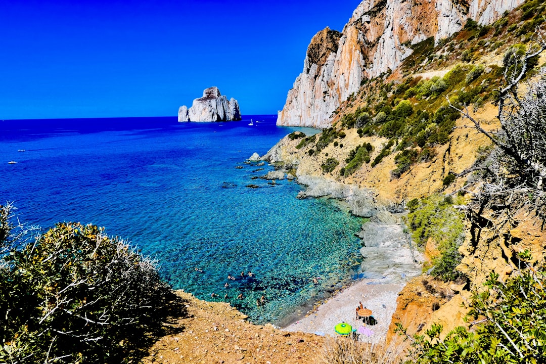 islet near cliff in the middle of body of water