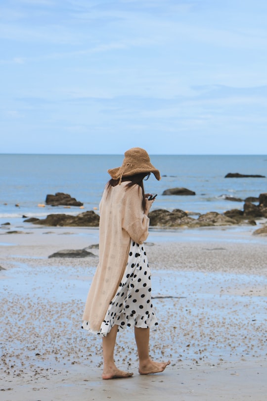 woman wearing sun hat walking along seashore in Hua Hin Beach Thailand