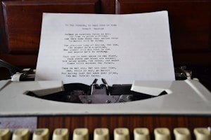 A typewritten sheet of paper is positioned in an old-fashioned typewriter. The sheet contains a poem with the title 'To the Virgins, to Make Much of Time' by Robert Herrick. The typewriter is set against a wooden background likely of a desk or cabinet.