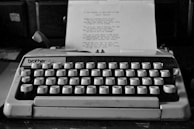 A vintage typewriter with a half-finished manuscript on a wooden desk surrounded by notes and pens.