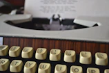 A close-up of a vintage typewriter with a royal purple ribbon threaded through the keys.