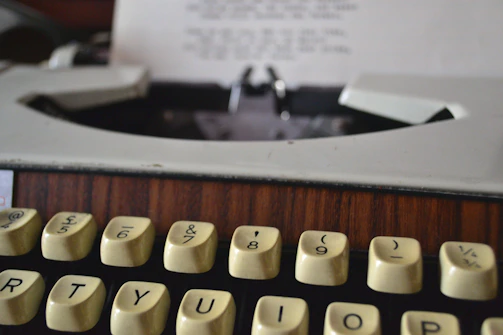 A close-up of a vintage typewriter with a royal purple ribbon threaded through the keys.