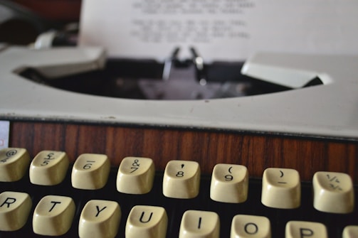 A close-up of a typewriter with a green-toned vintage postcard resting on the keys.