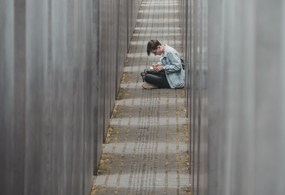 man sitting on pathway writing on paper