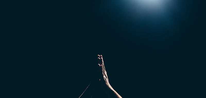 A person raising their hands toward a bright, open sky