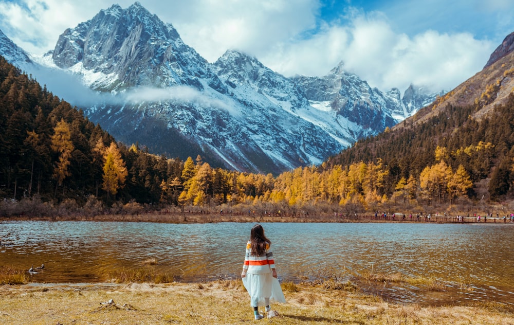 Frau steht vor einem See in der Nähe eines Berges