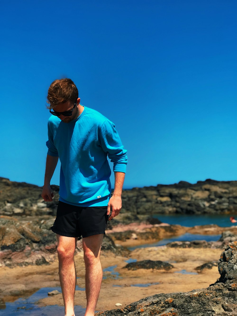uomo che indossa la camicia blu in piedi sulla roccia grigia durante il giorno