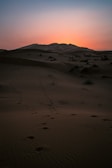 Sunset over the vast sand dunes of Mambrui, with footprints leading into the horizon.