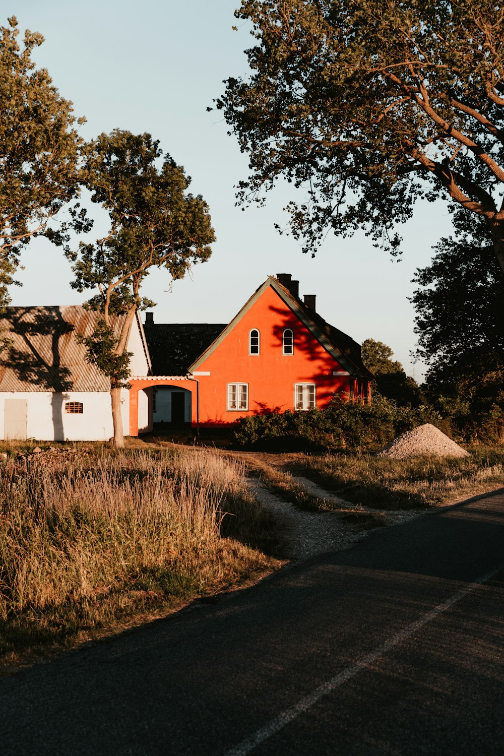 orangefarbenes Haus mit schwarzem Dach neben weißem Haus mit braunem Dach