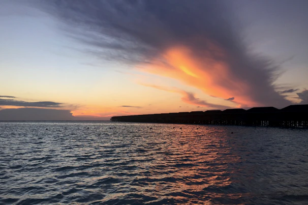 Sunset casting warm orange hues over overwater bungalows stretching into the calm sea