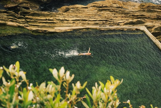 person swimming near brown cliff in Mystery Bay Australia