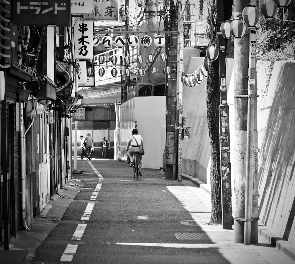 grayscale photo of man riding bike