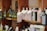 Several shelves display a variety of olive oil bottles. The bottles are in dark and light colors, with some wrapped in decorative packaging with tags. The shelves are wooden, and the setting appears to be a specialty or gourmet shop.