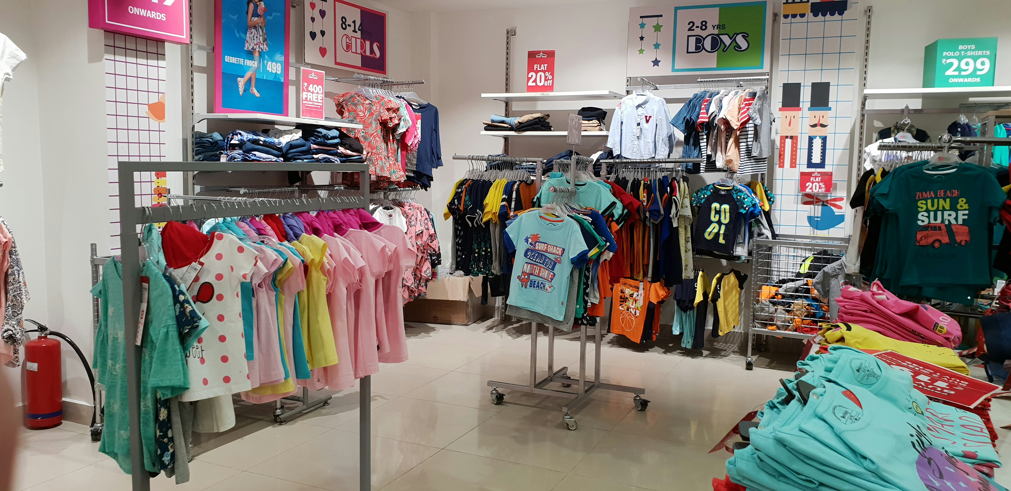 Cheerful kids clothing store with bright colourful outfits for children on display racks, well-lit open space