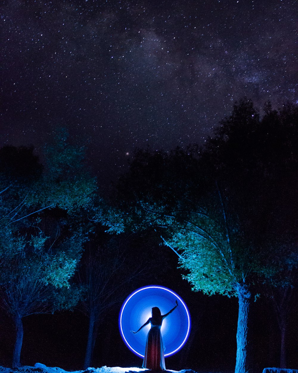 woman in dress standing in between trees