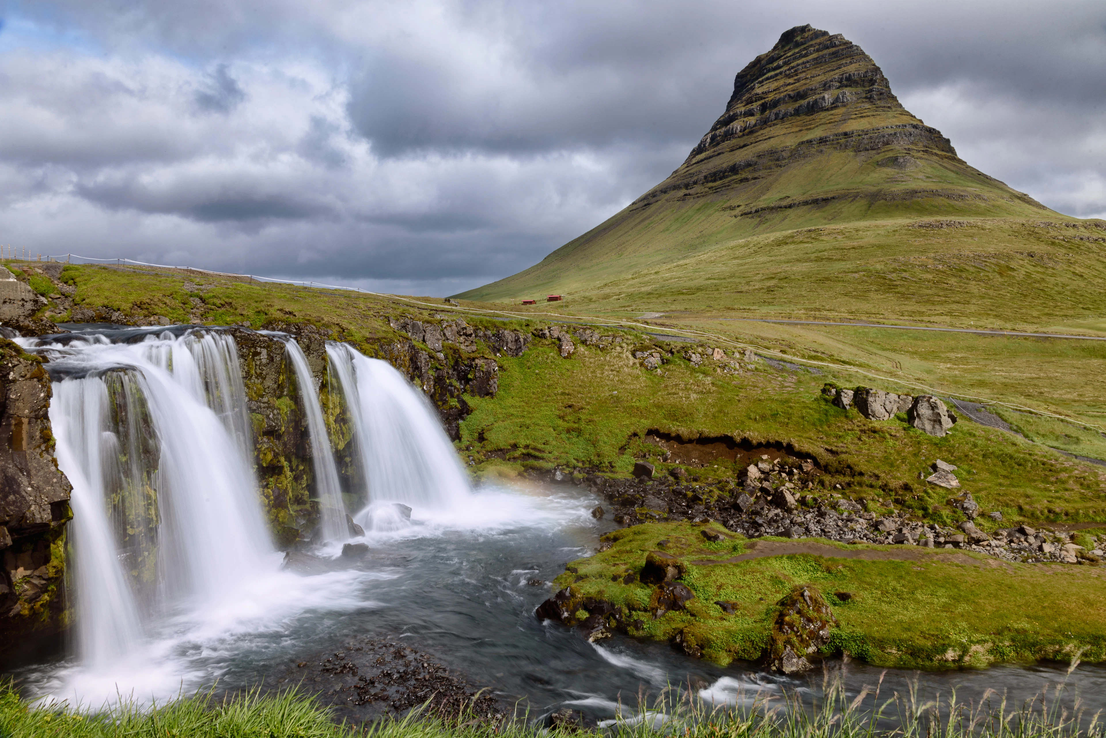 Kirkjufell mountain and the Kirkjufellsfoss falls in the green landscape of the Snæfellsnes peninsula