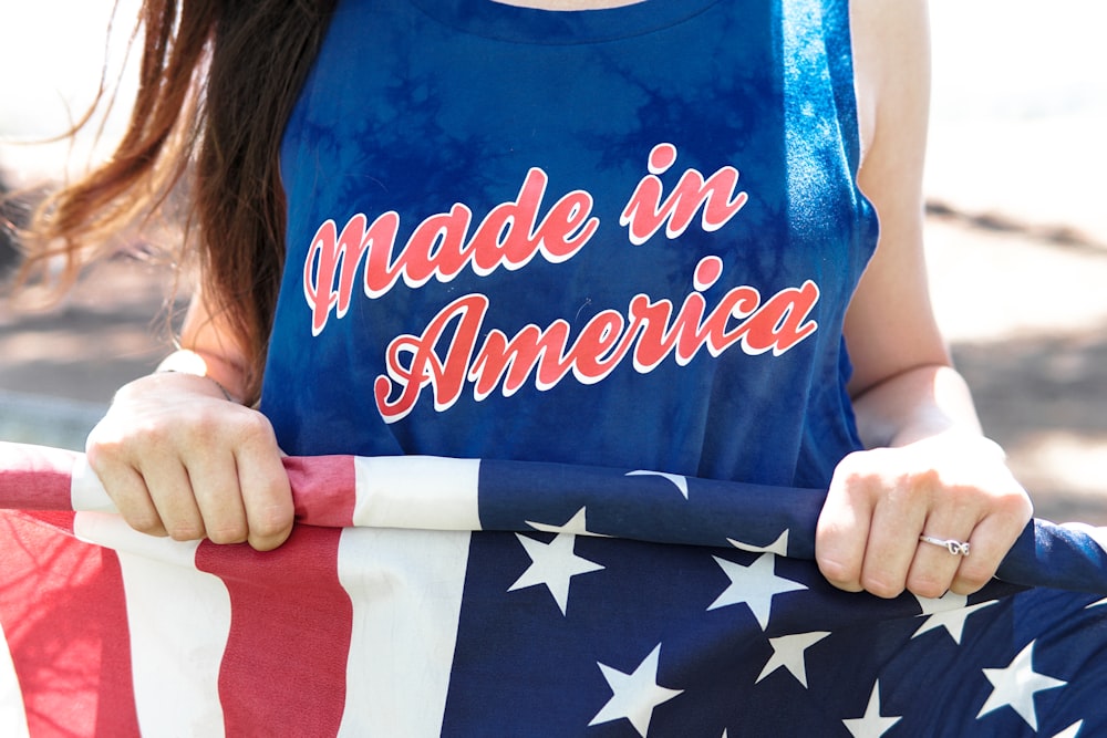 woman in blue sleeveless top holding flag of America