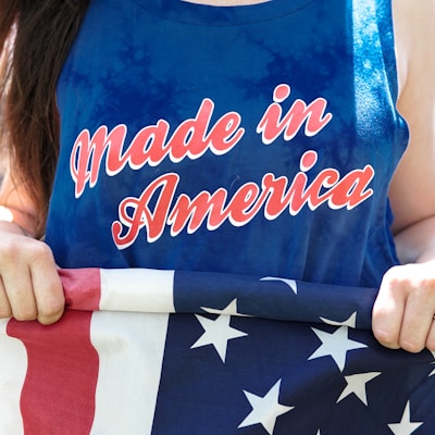 woman in blue sleeveless top holding flag of America