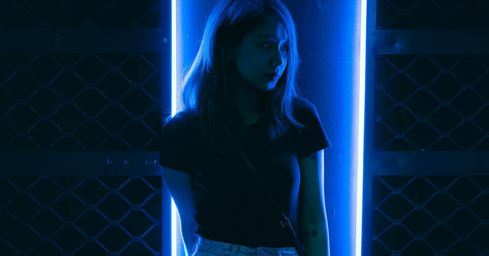 woman in black T-shirt standing in front of blue LED light