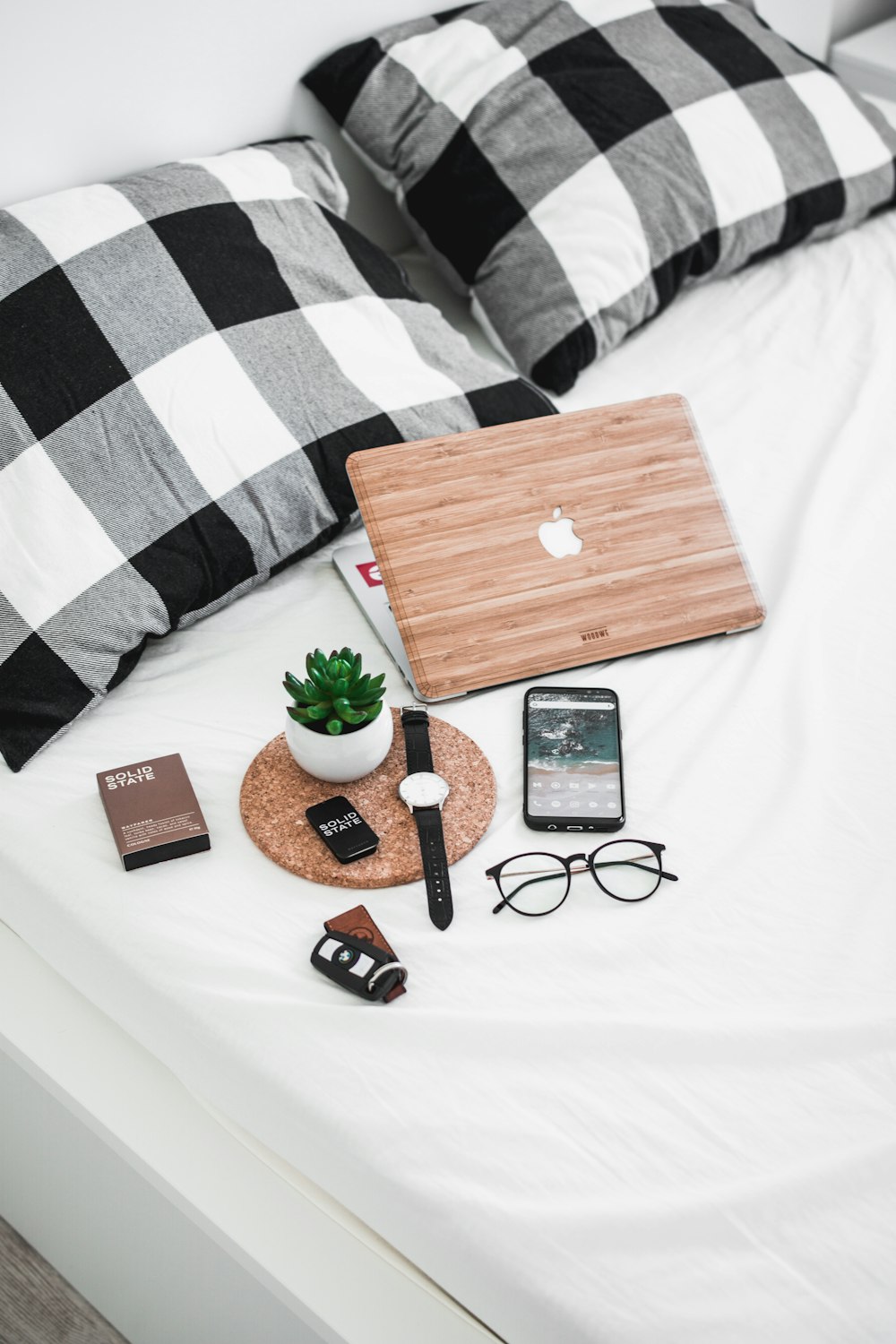 Smartphone, Brille, Uhr und Fahrzeuganhänger auf dem Bett