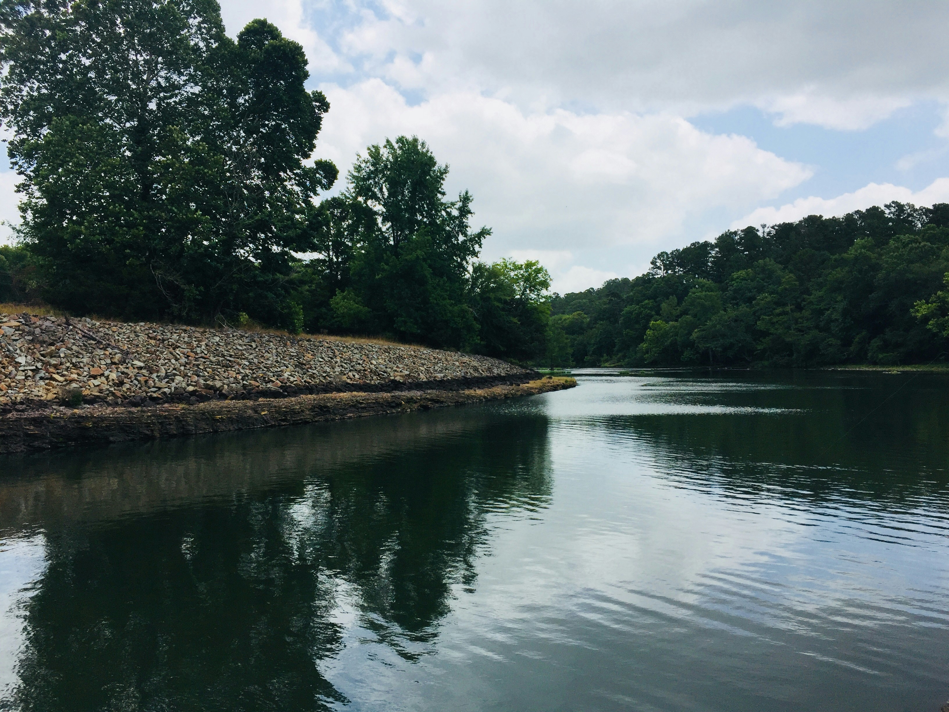 Calm lake surface reflecting cloudy sky in perfect stillness