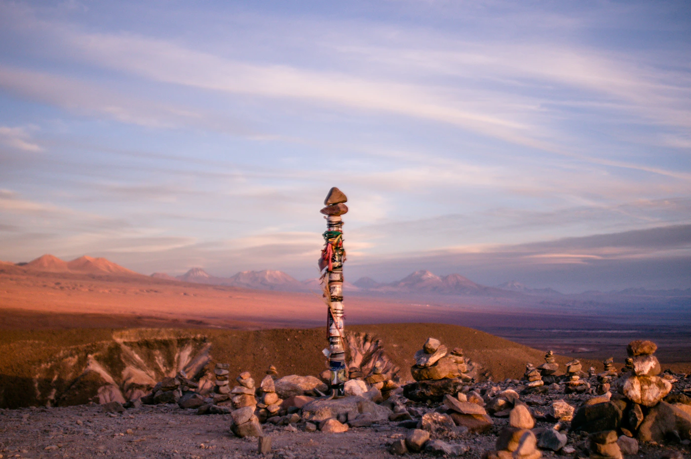 Atacama desert at dusk with distant mountains silhouetted against an orange and blue sky