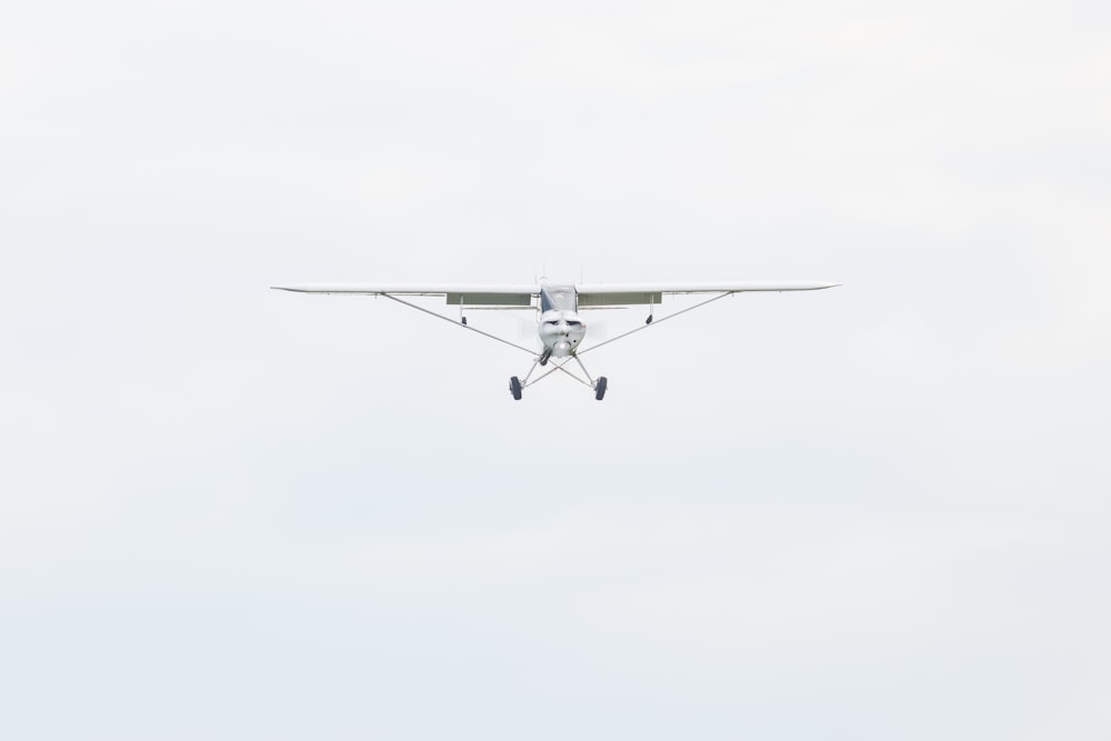 white monoplane flying during daytime