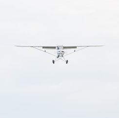 white monoplane flying during daytime