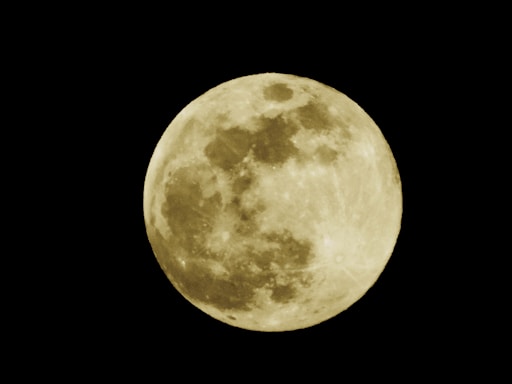 A bright full moon against a dark night sky, showcasing detailed lunar surface patterns and craters.