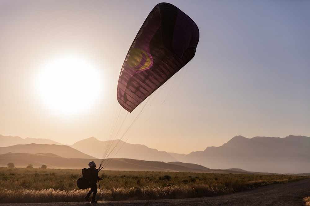 person in black jacket and pants riding on parachute during daytime