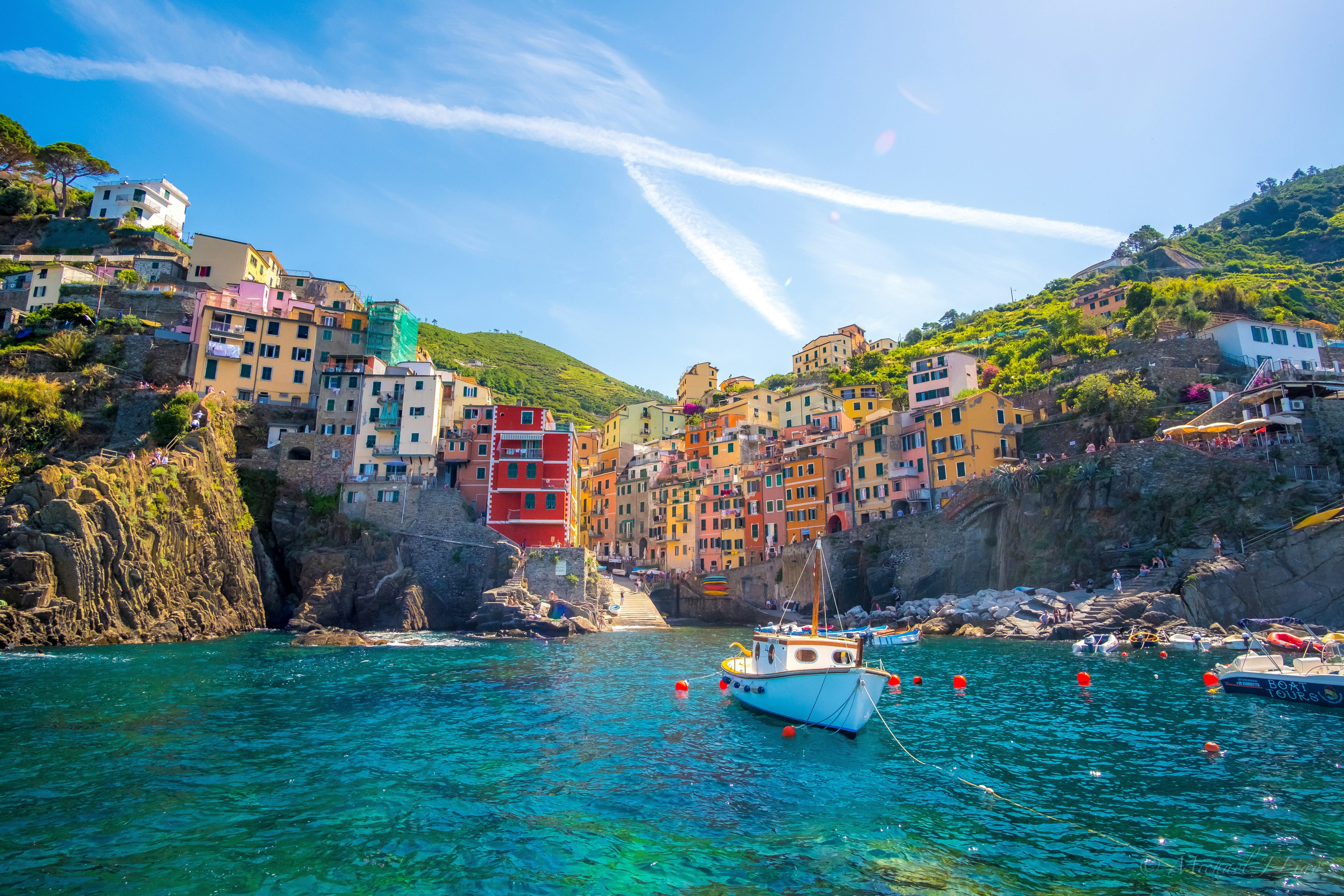 blue fishing vessel near houses on mountain