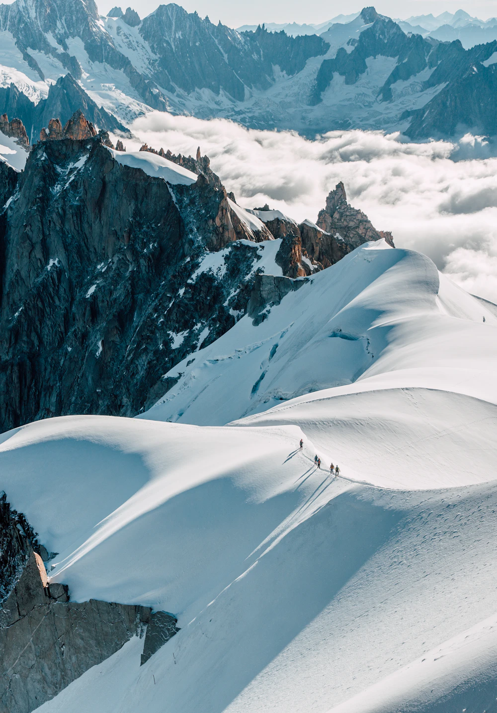 Roped alpinists ascending a snow arête high above Chamonix