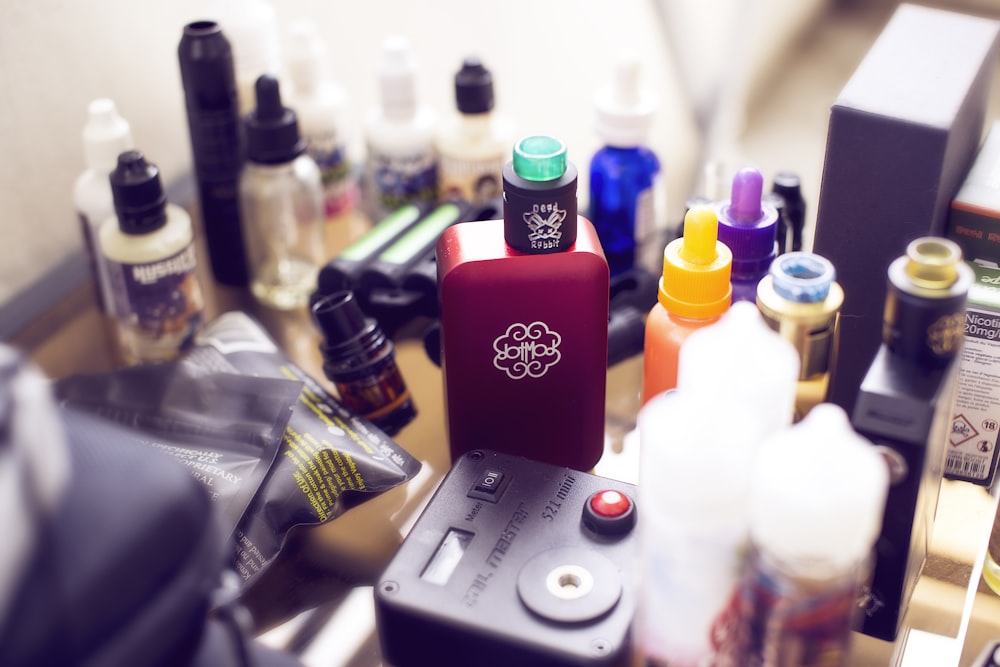 caixa vermelha mod vape ao lado de garrafas de suco eletrônico