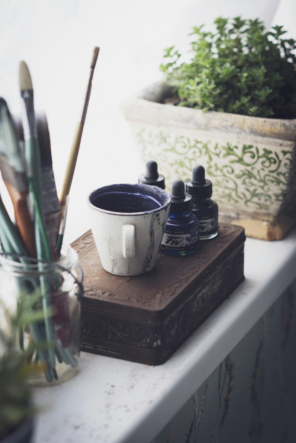 cup and ink bottles on top of chest box